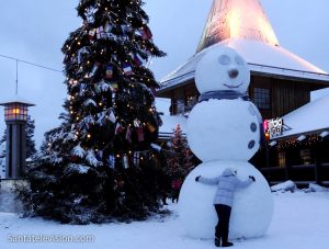 Le bonhomme de neige et le jeune voyageur dans le Village du Père Noël à Rovaniemi en Laponie