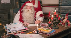 Le Père Noël écrit des cartes de voeux dans la Maison de Noël dans le Village du Père Noël à Rovaniemi