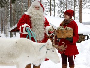 Babbo Natale e un elfo che nutrono una renna con i licheni in Lapponia finlandese