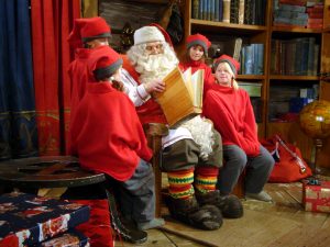 Weihnachtsmann zusammen mit seinen Elfen in seinem Büro in Rovaniemi